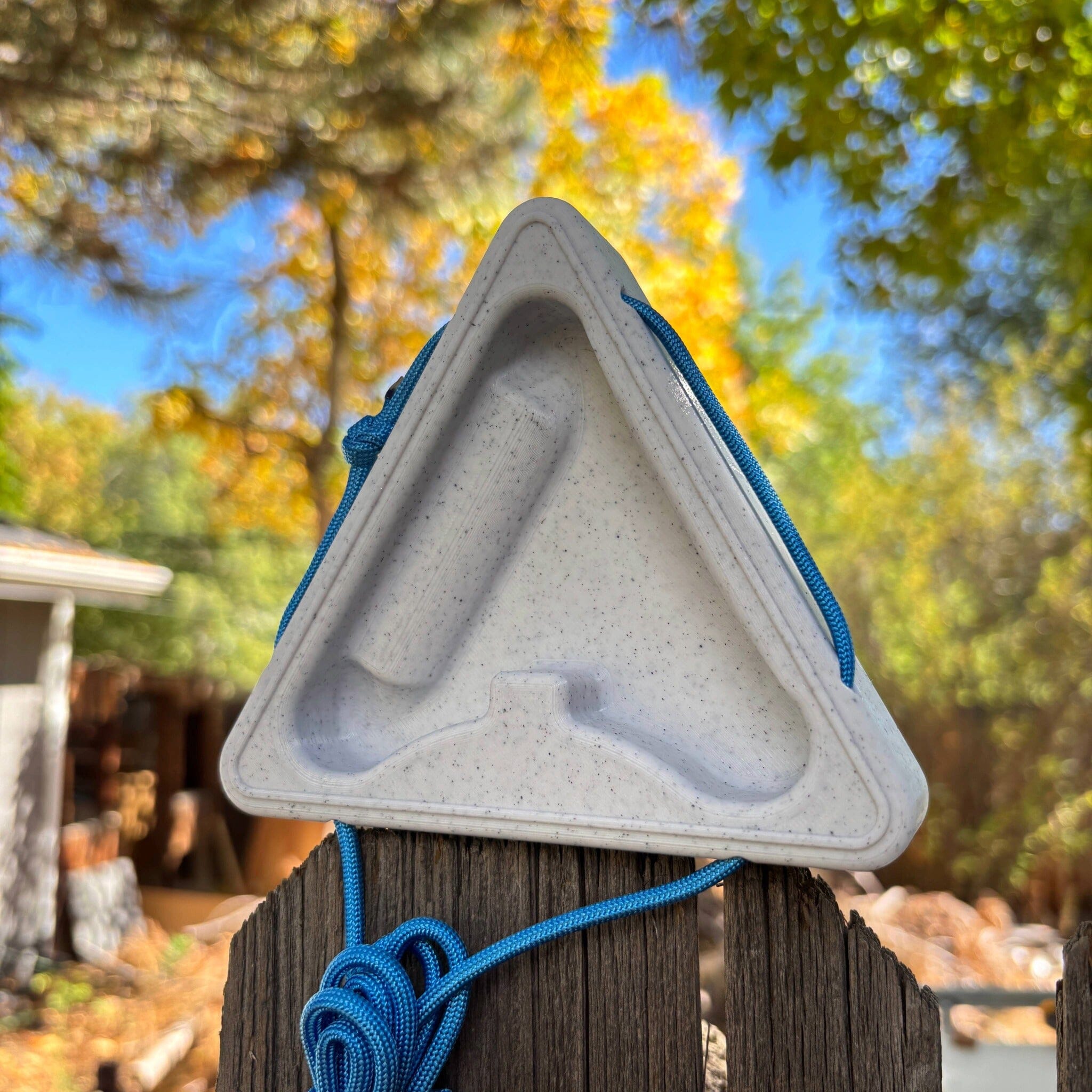 Triangular warm up block sitting atop a fence with a blurred natural background