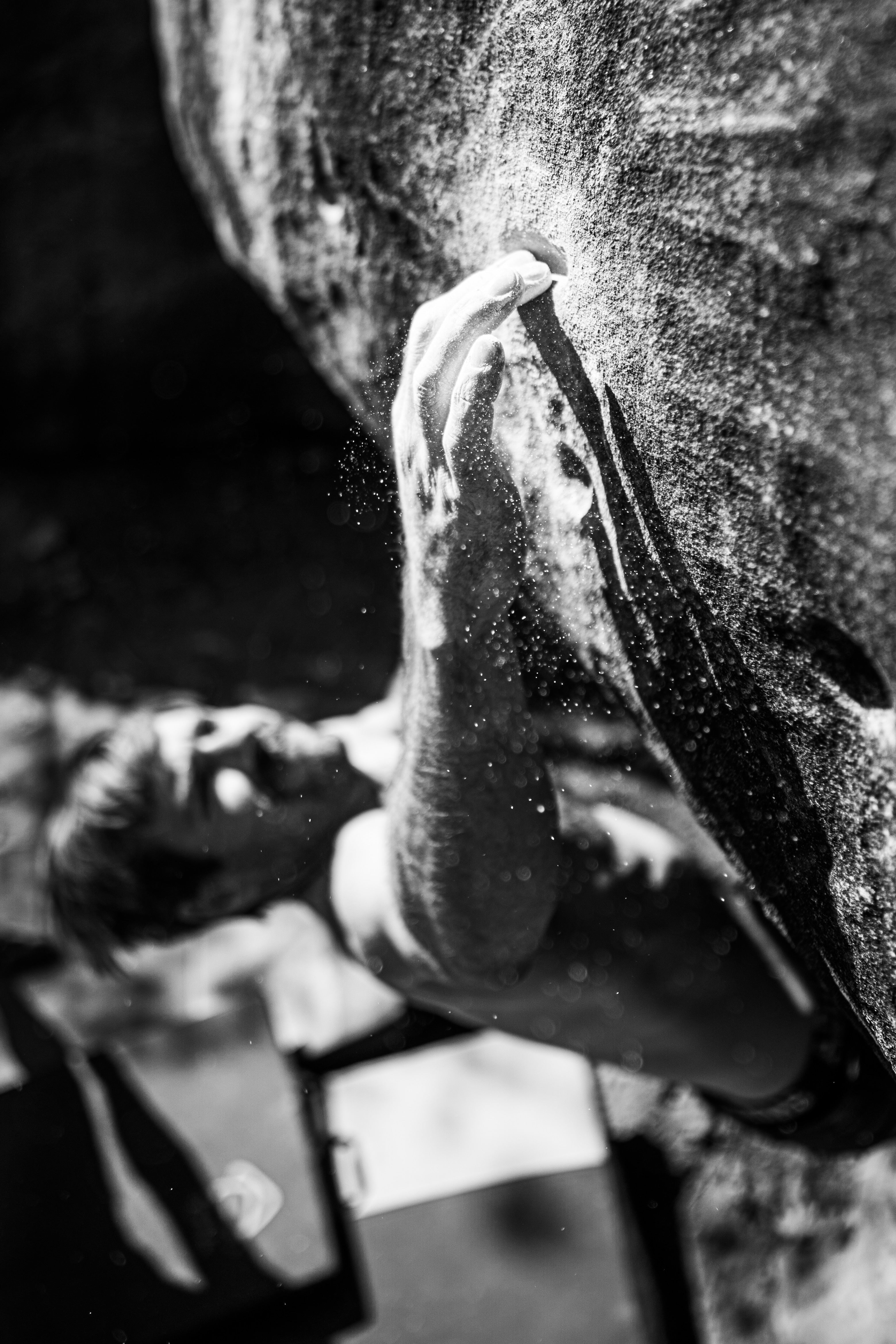 Close-up of a hand climbing on a rock face with chalk.