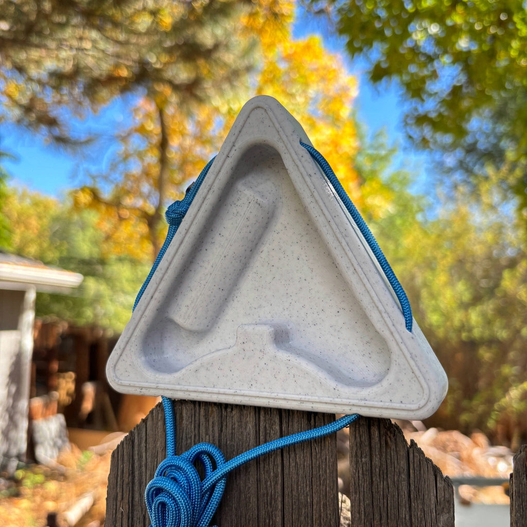 Triangular warm up block sitting atop a fence with a blurred natural background