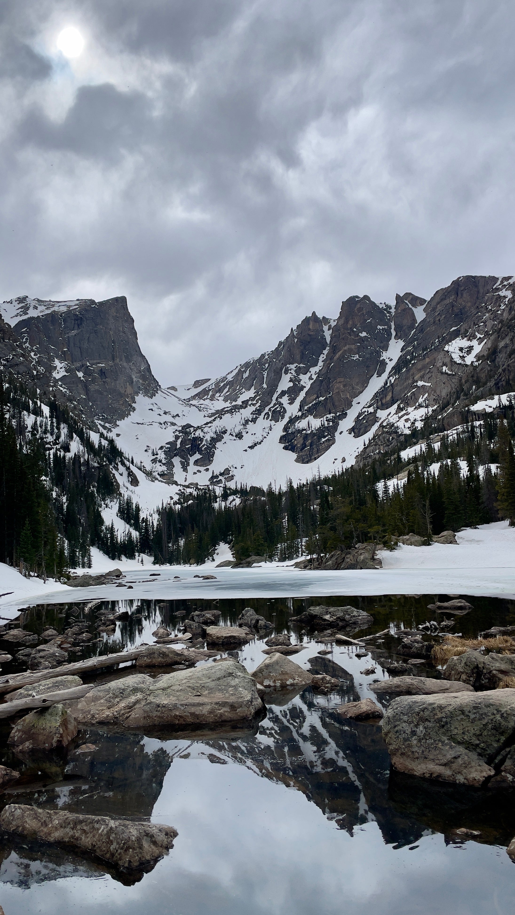 Mountain landscape with snow-capped peaks and a lake in the foreground. Chaos Canyon, Rocky Mountain National Park.