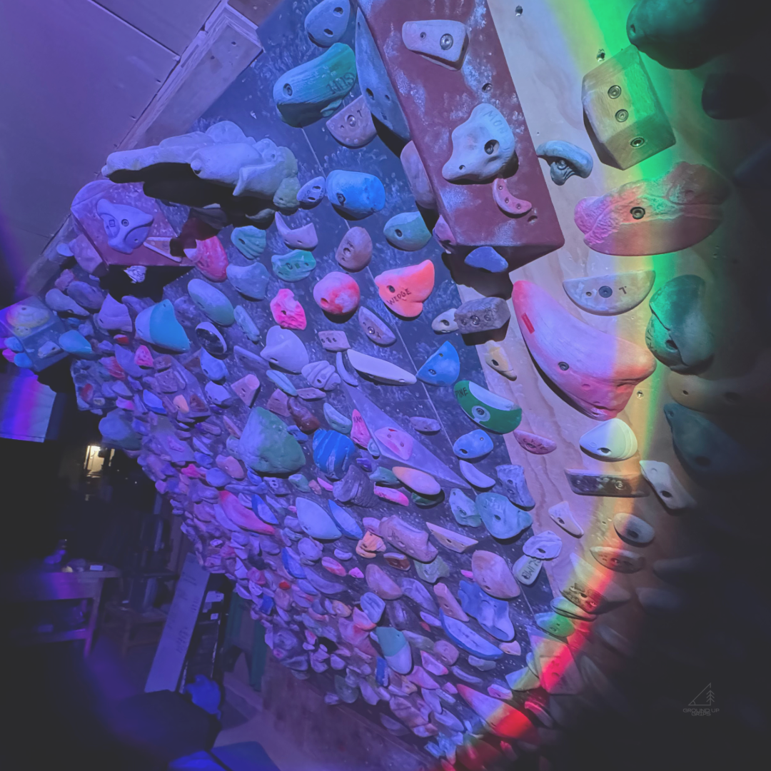 Colorful climbing wall with various holds illuminated by a rainbow light effect.